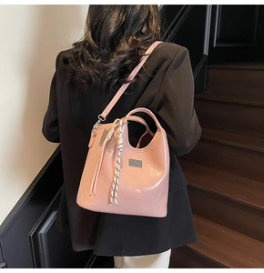 Sac à main rose matelassé avec plaque argentée porté par un mannequin sur un escalier
