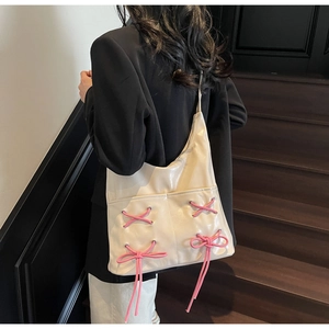 Detailed view of cream PU leather tote bag featuring stylish pink bow strap accents