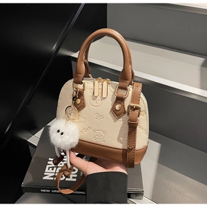 Detail of shell bag with embossed bear patterns and a white pompom charm
