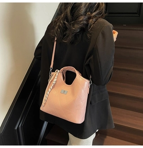 Sac seau matelassé rose avec détail foulard en soie porté par un mannequin sur escalier