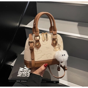 Detail of white shell bag with bear embossing, brown trim, and plush monster charm