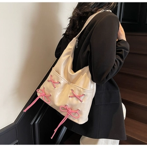 Detail of cream bucket bag featuring pink ribbon bow accents and premium PU leather texture