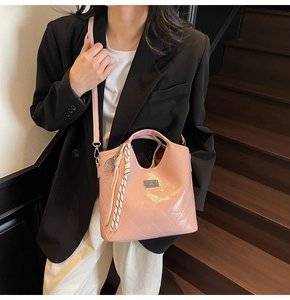 Détail d'un sac bandoulière rose matelassé avec fermoir rotatif argenté et pendentif
