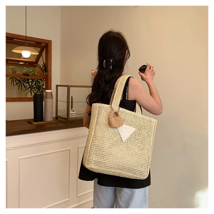 Vue lifestyle d'un sac cabas tissé beige avec pendentif tricoté dans un café cosy