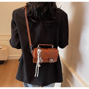 Detail of brown cylinder bag featuring cartoon embossing and silver twist lock closure
