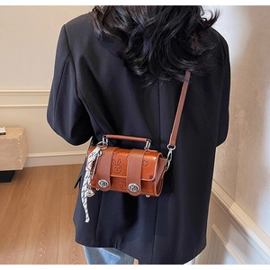 Detail of brown faux leather crossbody bag with rabbit embossing and checkered ribbon bow