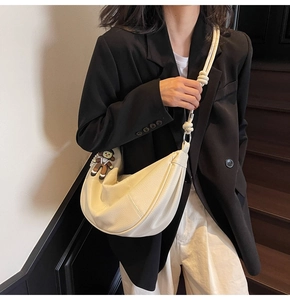 Detail view of cream crescent bag with lychee texture leather and knotted strap detail