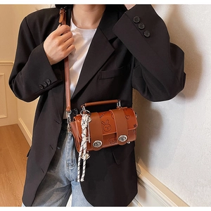 Detail of vintage brown mini bag with cartoon embossing and decorative woven rope strap
