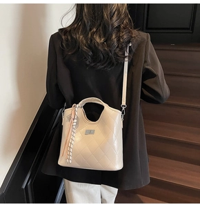 Détail d'un sac bandoulière beige matelassé avec fermoir pivotant et pompon rose