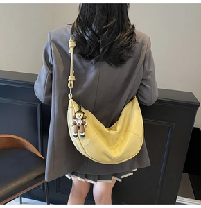 Detail of yellow pebbled leather crescent tote bag with knot strap and cute charm