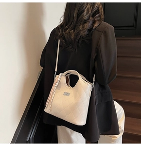 Détail d'un sac à main matelassé blanc cassé avec foulard rayé et pendentif pompon