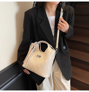 Détail d'un sac seau matelassé beige avec foulard en soie et pendentif à pompon rose