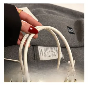 Detailansicht des glatten weißen Ledergriffs mit goldenen Metallringen an der Handtasche