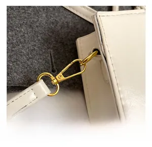Makrodetail des hochwertigen goldenen Metallhakens und der Nähte an weißer Handtasche