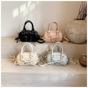Quatre sacs Boston avec nœuds en noir, rose, beige et gris sur des marches en pierre