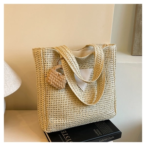 Détail du sac fourre-tout en paille tissée beige avec patch et mini pendentif de sac