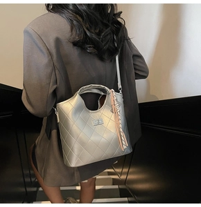 Sac fourre-tout argenté matelassé avec pompon à franges porté par un mannequin