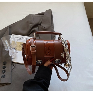 Detail of a brown leather pillow bag featuring a rabbit embossed design and metal clasps