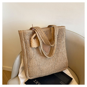 Détail de la texture d'un sac cabas beige en paille tressée avec empiècement en cuir