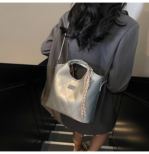 Sac bandoulière matelassé argenté avec finition métallique et breloque tissée