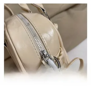 Gros plan sur les ferrures argentées et le zip d'un sac Boston beige élégant