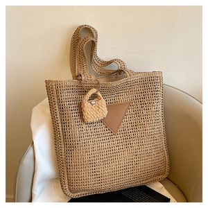 Détail d'un sac cabas en paille tressée avec empiècement en cuir et mini charm décoratif