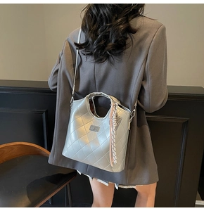 Sac seau matelassé argenté avec texture métallique et bandoulière porté par mannequin