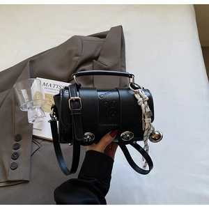 Detail of black cylinder pillow bag with silver turn-lock and rabbit relief charm