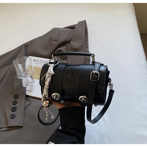 Detail of black leather pillow bag featuring rabbit relief and decorative bell charm