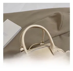 Détail des poignées en similicuir crème et des anneaux métalliques du sac Boston