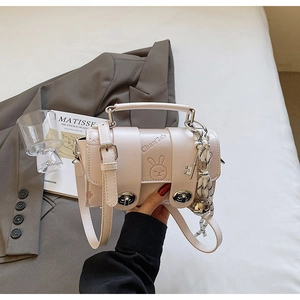 Detail of pink PU leather handbag with rabbit embossing and elegant silk scarf accessory