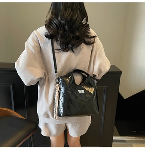 Détail du sac bandoulière matelassé noir avec fermoir rotatif et pompon tissé coloré