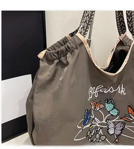 Détail de la broderie papillon et de la sangle ondulée sur le grand sac cabas