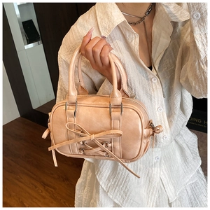 Détail d'un sac Boston abricot avec décoration de nœud papillon tenu par un modèle