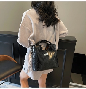 Vue de dos d'un mannequin portant un sac cabas en cuir matelassé noir à fermoir argenté