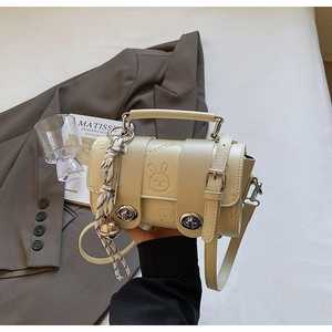 Detail of beige PU leather crossbody bag with cartoon embossing and silk scarf charm