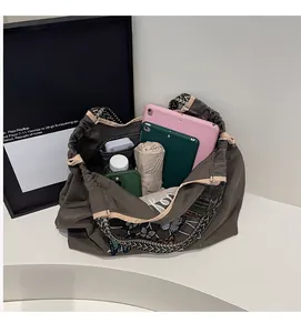 Détail de l'intérieur d'un grand sac en toile avec broderie papillon et objets rangés