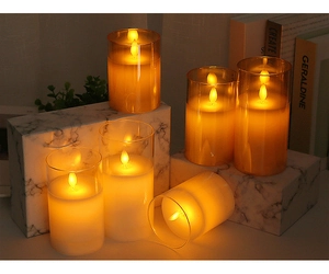 Dettaglio candele LED in vetro ambrato su base di marmo con luce gialla calda