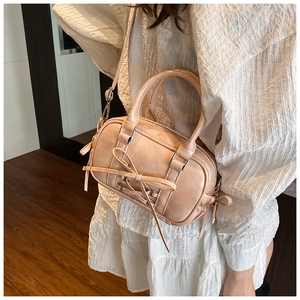 Détail du sac Boston rose avec nœud papillon en cuir mat et bandoulière réglable