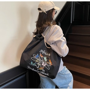 Détails des papillons brodés et du lettrage sur le grand sac fourre-tout en toile noire