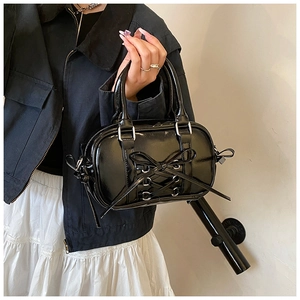 Gros plan du sac Boston en cuir verni noir avec nœud décoratif et détails de rubans