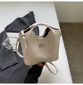 Détail du sac cabas matelassé crème avec fermoir rotatif argenté sur une veste grise