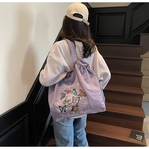 Détail du cabas en toile violette avec broderie papillon et bretelles tissées