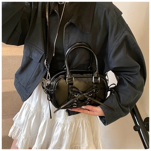 Détail du sac Boston en cuir verni noir avec nœud papillon et finitions argentées