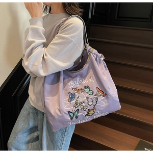 Détail du sac cabas en toile violette avec imprimé papillon et bandoulières tissées