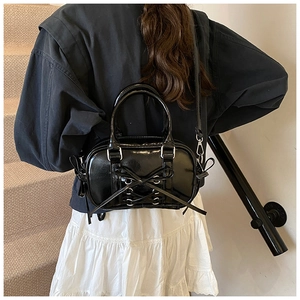 Détail d'un mini sac Boston noir brillant avec un nœud élégant et une boucle métallique