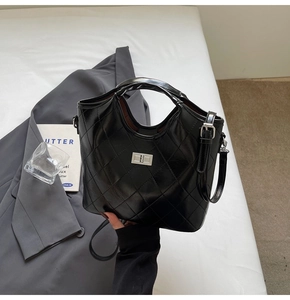 Détail d'un sac à main en cuir noir matelassé avec fermoir argenté et bandoulière