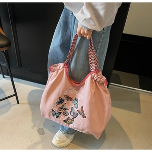 Détail du sac en toile rose avec imprimé papillon et poignées tissées à cordon