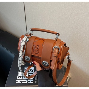 Macro detail of caramel PU leather bag with cartoon embossing and silver metal clasp