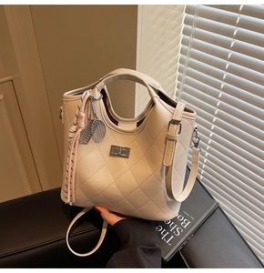 Détail du sac matelassé crème avec fermoir rotatif argenté et breloque de tennis tissée